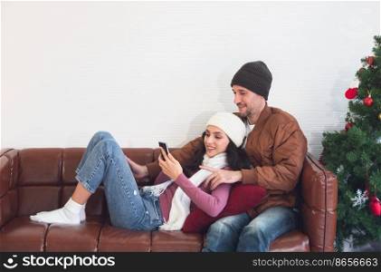 Smiling couple having fun with smartphone taking selfie at home. Happy woman relaxing on couch with boyfriend holding cellphone enjoying media content in living room