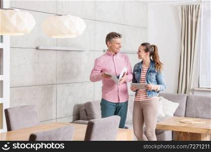 Smiling couple holding agreement papers while standing in apartment