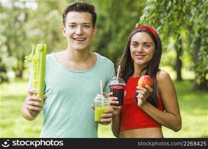 smiling couple holding avocado apple smoothies hand