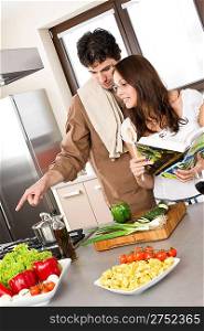 Smiling couple in modern kitchen cook together with cookbook