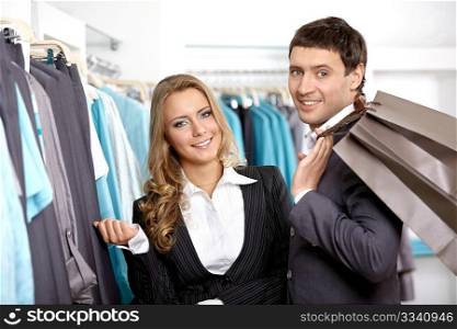 Smiling couple in shop of clothes with purchases