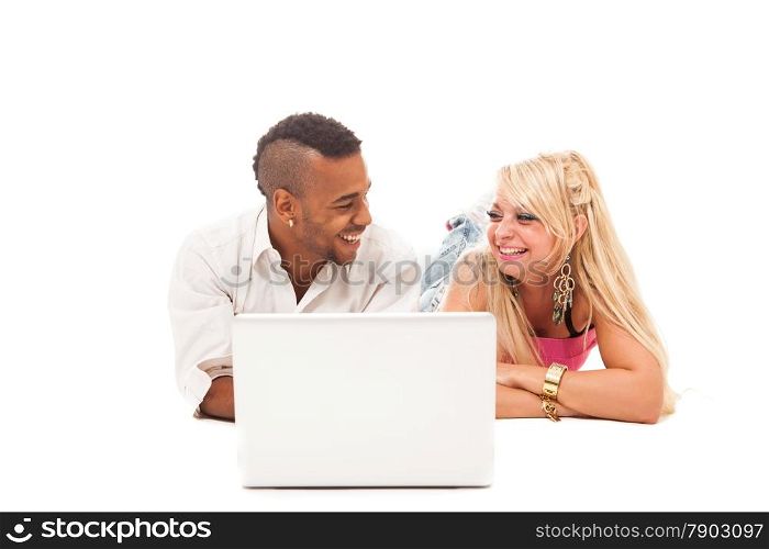 Smiling couple lying on the floor with notebook over white isolated background