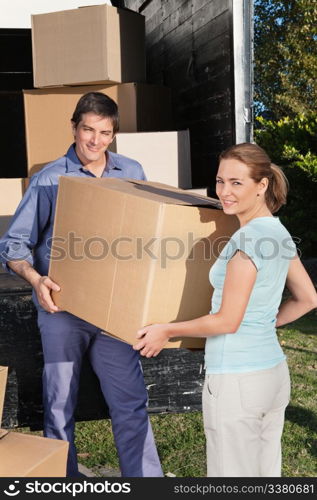 Smiling couple moving boxes at their new home