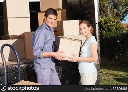 Smiling couple moving luggage at their new house