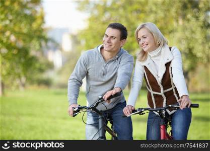 Smiling couple on bicycles in the park