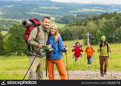 Smiling couple posing with hiking sticks and map on track