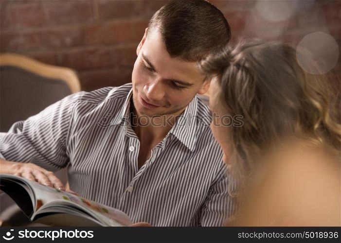 Smiling couple reading menu and choosing meal at loft style restaurant