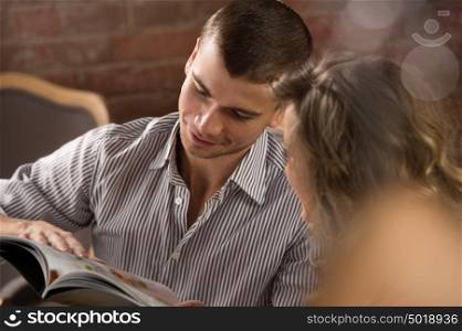 Smiling couple reading menu and choosing meal at loft style restaurant