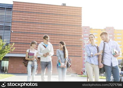 Smiling couple walking with friends in college c&us