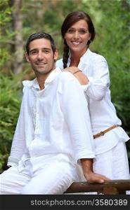 Smiling couple wearing white in a garden