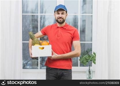 smiling courier with box fruits