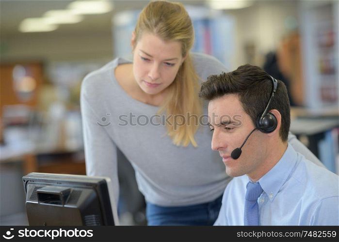 smiling coworkers sit by the table in headphones