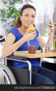smiling crippled woman sitting in a wheel chair having breakfast