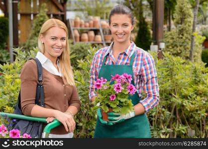 Smiling customer and worker in garden center holding potted plant