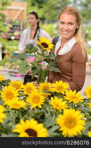 Smiling customer woman shopping for potted sunflower in garden center