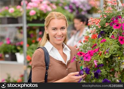 Smiling customer woman with colorful flowers in garden center
