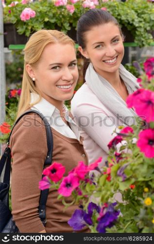 Smiling customer women in garden center shopping for colorful flowers