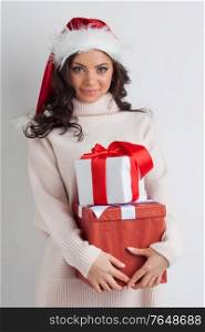 Smiling cute girl in red christmas hat holding gift boxes. Girl with christmas gift box