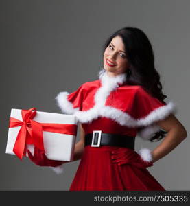 Smiling cute girl in red christmas outfit holding gift box. Girl with christmas gift box