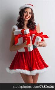 Smiling cute girl in red christmas outfit holding gift boxes. Girl with christmas gift box
