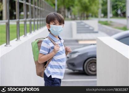 Smiling cute little boy with school backpack and protective face mask ready for first day of school during covid pandemic. Black kid going back to school during coronavirus pandemic disease.