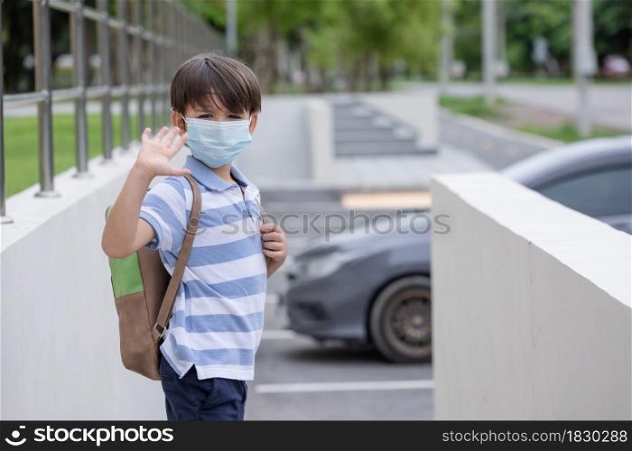 Smiling cute little boy with school backpack and protective face mask ready for first day of school during covid pandemic. Black kid going back to school during coronavirus pandemic disease.