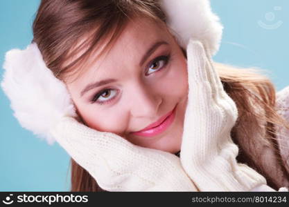 Smiling cute pretty woman girl in earmuffs.. Portrait of smiling cute pretty woman in earmuffs. Happy lovely girl in studio on blue.