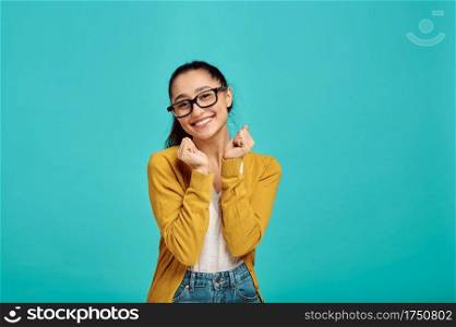 Smiling cute woman in glasses, blue background, positive emotion. Face expression, female person looking on camera in studio, emotional concept, feelings. Smiling cute woman in glasses, positive emotion