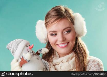 Smiling cute woman with little snowman. Winter.. Smiling pretty cute woman holding little snowman. Attractive girl in earmuffs and scarf in studio on green. Winter fashion.