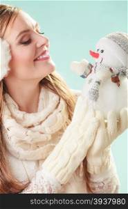 Smiling cute woman with little snowman. Winter.. Smiling pretty cute woman holding little snowman. Attractive girl in earmuffs and scarf in studio on green. Winter fashion.