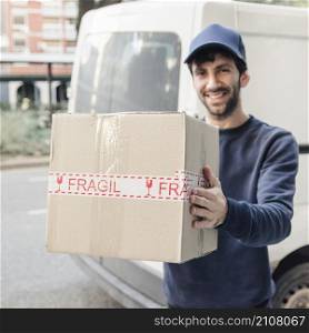 smiling delivery man holding cardboard box