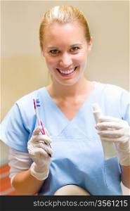 Smiling dental hygienist hold toothbrush and toothpaste white smile