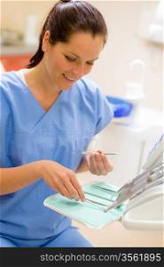 Smiling dentist woman prepare dental tools at modern surgery office