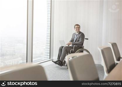 Smiling disabled businessman with laptop in boardroom at modern office