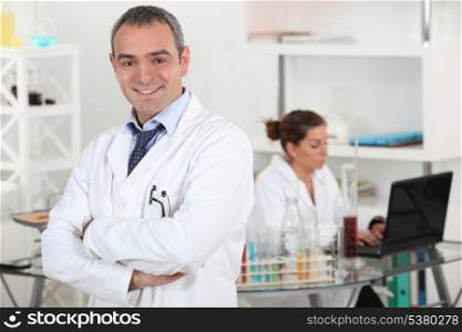 smiling doctor cross-armed in lab