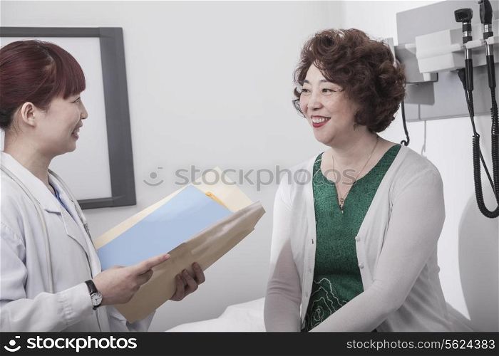 Smiling doctor holding a medical chart and consulting with a patient
