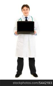 Smiling doctor holding laptop with blank screen in hands isolated on white&#xA;
