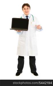 Smiling doctor pointing finger on laptop with blank screen isolated on white&#xA;