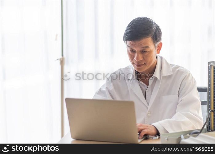 Smiling Doctor Using Laptop On Table