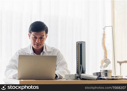 Smiling Doctor Using Laptop On Table