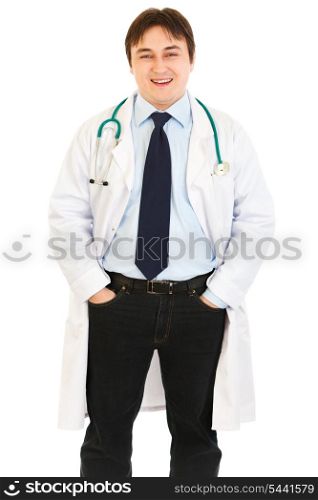 Smiling doctor with stethoscope keeping his hands in pockets isolated on white&#xA;