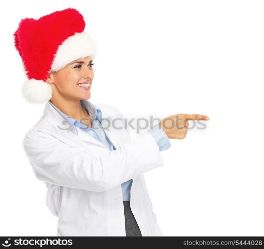Smiling doctor woman in santa hat pointing on copy space