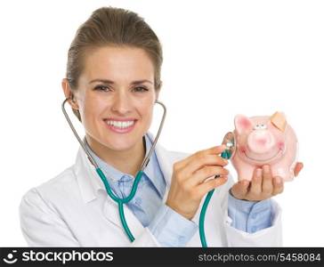 Smiling doctor woman listening piggy bank with stethoscope