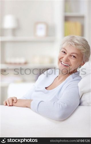 Smiling elderly woman at home on the couch