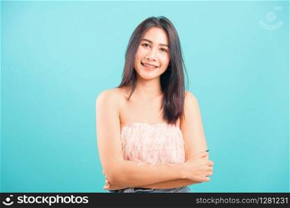 Smiling face Asian beautiful woman her cross arm looking to camera on blue background, with copy space for text