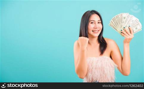 Smiling face portrait asian beautiful woman cheerful her holding money and her looking to camera on blue background, with copy space for text