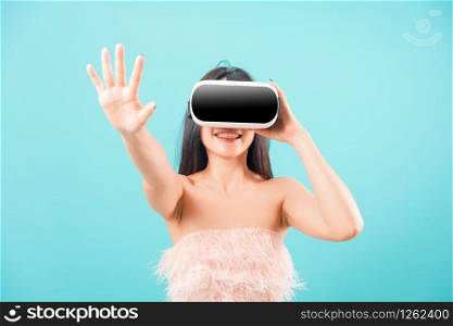 Smiling face portrait asian beautiful woman her use glasses of virtual reality (VR) technology and touch air on blue background, with copy space for text