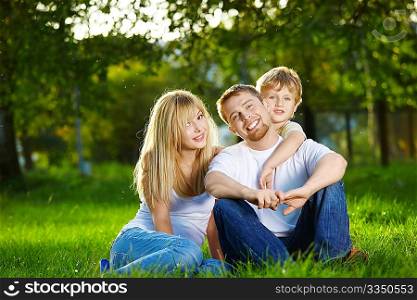 Smiling family has rest on a summer lawn