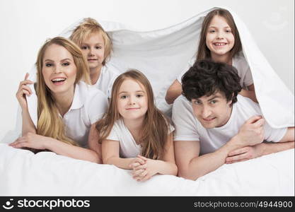 Smiling family in bed. Smiling family with three children wake up in bed