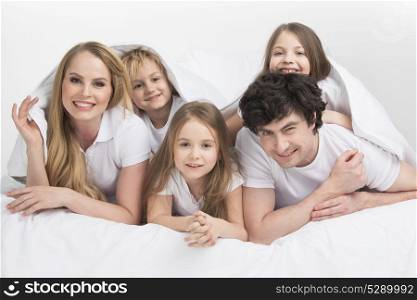 Smiling family in bed. Smiling family with three children wake up in bed